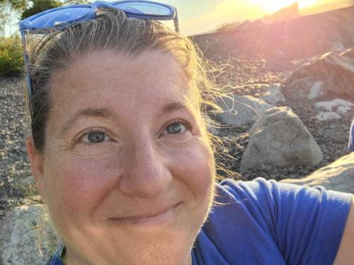 Image of Sashya Clark, Your Strategic Partner & Human Design Specialist at the beach with sunglasses on.