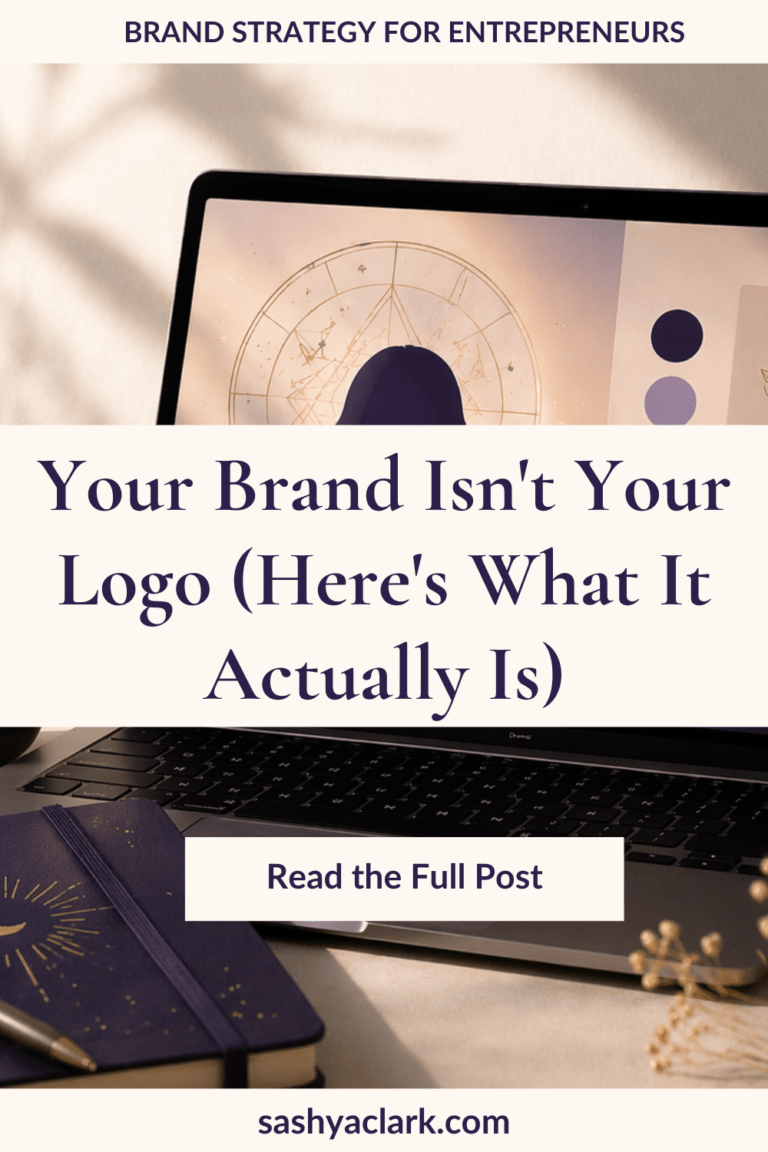 Pinterest pin graphic with cream and navy design. A laptop displays an astrology birth chart on screen alongside navy and lavender color swatches. A celestial moon-design notebook and dried flowers rest below the keyboard. Text reads: Your Brand Isn't Your Logo (Here's What It Actually Is). Brand strategy for entrepreneurs. sashyaclark.com